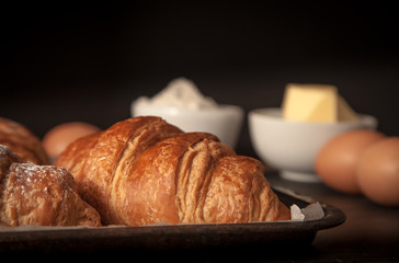 Two fresh croissants with ingredients in the background