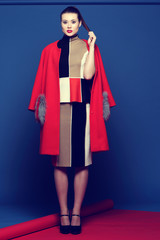 Fashion portrait of young asian woman in trendy skirt, top and red coat.