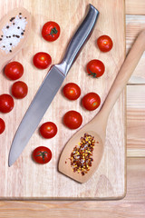 Naklejka na ściany i meble Fresh vegetables - tomato cherry and knife on wooden board on table background. Top view. Healthy food concept.
