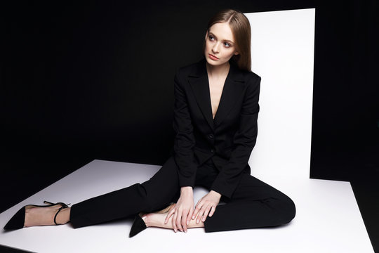 High fashion portrait of young elegant woman in black suit.