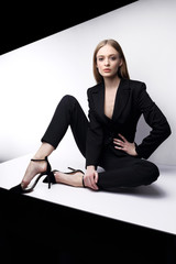 High fashion portrait of young elegant woman in black suit.