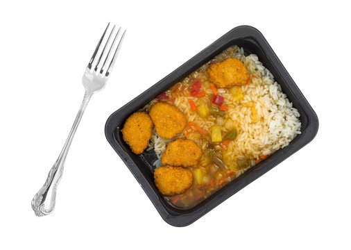 Top view of a sweet and sour chicken TV dinner with a fork to the side isolated on a white background.