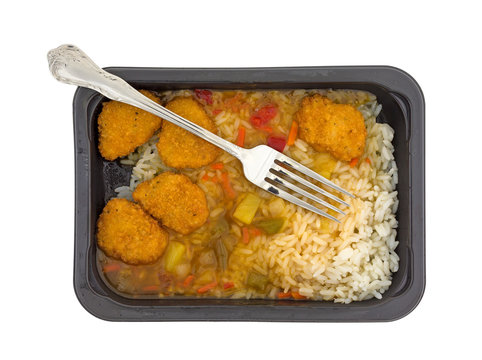 Sweet and sour chicken TV dinner with a fork in the food isolated on a white background top view.