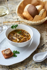 Asian cuisine. Mushroom soup with egg noodles served with toast, bread and white wine on marble background.