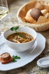 Asian cuisine. Mushroom soup with egg noodles served with toast, bread and white wine on marble background.