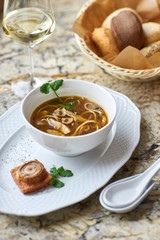 Asian cuisine. Mushroom soup with egg noodles served with toast, bread and white wine on marble background.