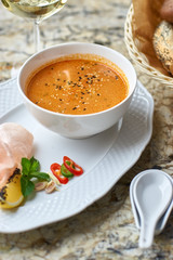 Peranakan cuisine. Singapore Laksa soup served with glass of white wine, bread, ceramic spoon, crab chips, slice of lemon and fresh vegetables on marble table