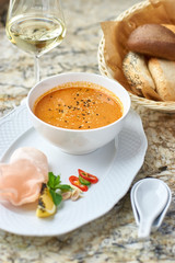 Peranakan cuisine. Singapore Laksa soup served with glass of white wine, bread, ceramic spoon, crab chips, slice of lemon and fresh vegetables on marble table