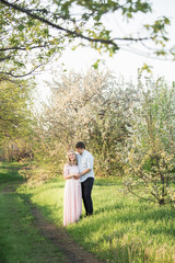 Young parents in a spring park at sunset. Pregnant woman.