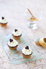 Chocolate Vanilla Mini Cupcakes decorated with chocolate hearts on transparent glass board, on light beige background.