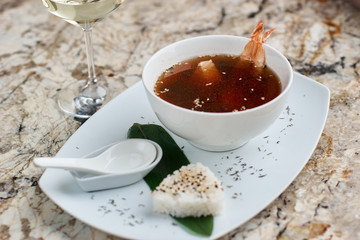 Japanese cuisine. Suimono or Matsutake soup served in white ceramic plate with spoon, rice and white wine on marble background.