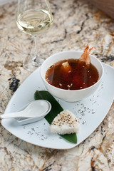 Japanese cuisine. Suimono or Matsutake soup served in white ceramic plate with spoon, rice and white wine on marble background.