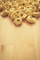 dry raw pasta tortellini on wood rustic background with copy space 