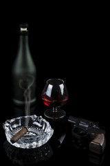 Glass of cognac with a cigar and revolver