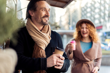 Dreamful senior guy enjoying hot beverage outside