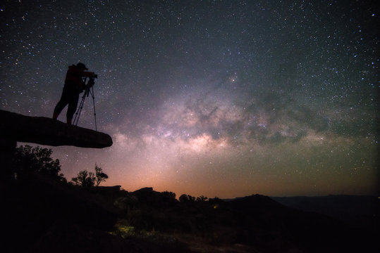 Cameraman takes photo of milky way on Stone lodge under night sky stars