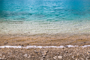 green blue water sea ocean background texture with pebbles.