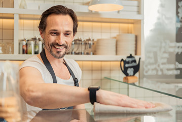 Cheerful salesman cleaning working place