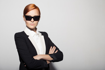 Fashion portrait of serious woman dressed as a secret agent or spy. Gray background.