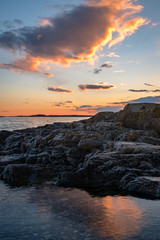 Landscape image of clouds lighting up over rocks during sunset