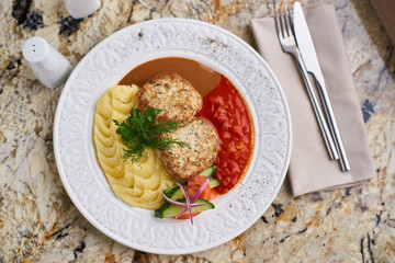 Chicken breast cutlets with mashed potatoes served with mushroom and tomato sauces on white plate on marble table. Top view or flat lay.