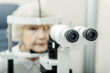 Old lady sitting near optical apparatus