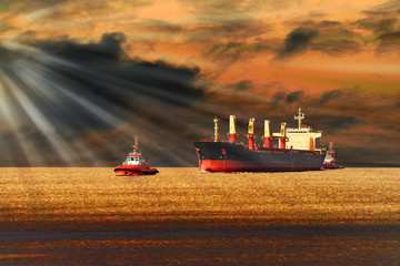 Tugboats towing a large cargo ship on sea.