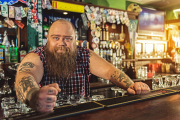 Fototapeta na wymiar Happy bearded man standing at counter near drinks