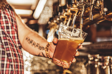 Male arm filling cup of beer