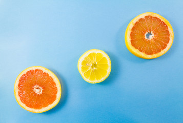 One grapefruit and two lemon slices on blue background.