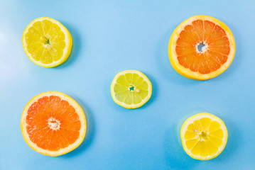 Two grapefruit and three lemon slices on blue background.