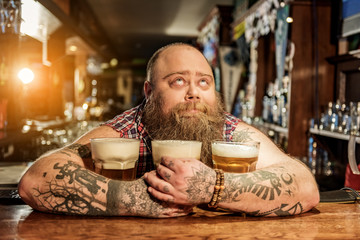 Pensive male embracing mugs of alcohol beverage