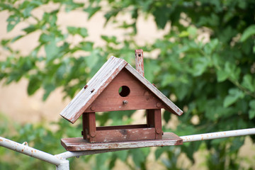 Brown wooden birdhouse with foliage blurred in background