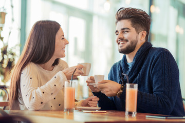 Young couple sitting in cafe by a window and laughing