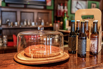Pie and bottles of beer locating on bar