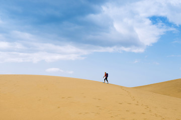 One man walks to the top of the dunes in the desert