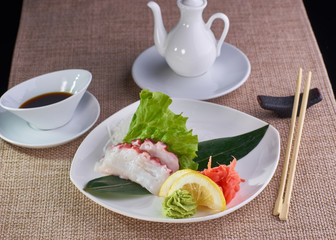 Japanese cuisine. Sashimi with octopus served with soy sauce and chopsticks on table.
