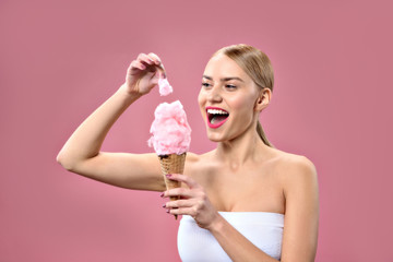 Smiling young woman holding piece of cotton candy