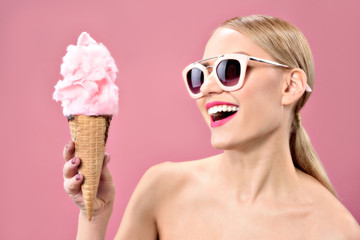 Smiling young woman having fun with candy floss