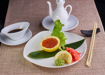 Japanese cuisine. Sashimi with salmon caviar served with soy sauce and chopsticks on table.