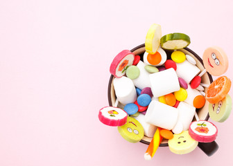 Lollipops sweets in cup. Candy mm, top view flat lay on pink background. Sweet sucker, lollipop, candy, isolated minimal concept above decoration, food background