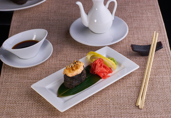 baked sushi with salmon served with chopsticks and soy sauce on table