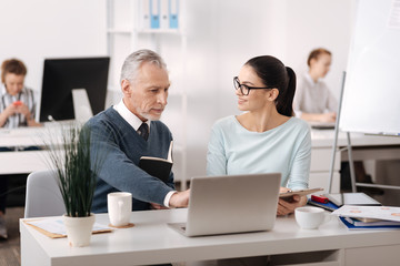 Positive delighted brunette listening to her colleague