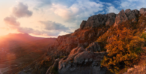 Crimean autumn mountain landscape with a setting sun, backlit orange trees and a beautiful cloudy sky.Demerdzhi mountain range is considered to be one of the most picturesque in the Crimea. Russia.