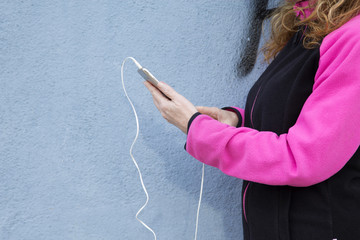 Woman athlete with mobile phone on the street listening to music