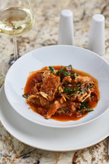 Vegetables tempura in sweet and sour sauce served in white round plate with glass of white wine on marble table