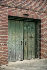 Old wooden doors on an abandoned brick building with a shallow depth of field