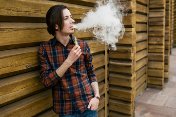 attractive young man smokes an electronic cigarette