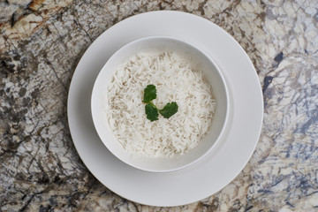 White bowl with white boiled rice on marble table