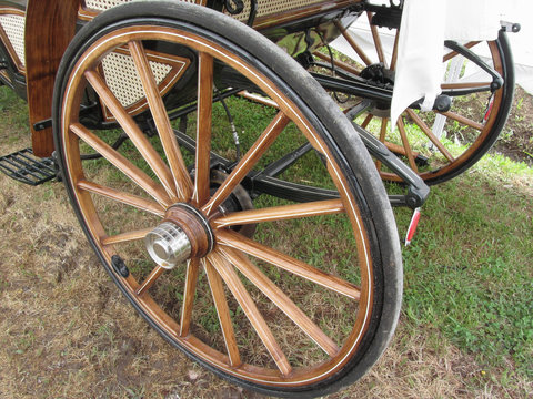 Rear wheels of old-fashioned horse carriage on green grass